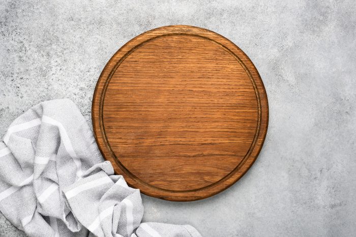 Round wooden cutting board on grey concrete background