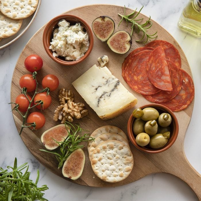 cheese, tomatoes, chorizo, crackers, olives on a round timber board, platter.
