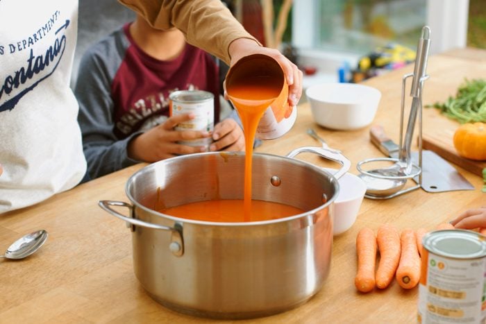 tomato soup being poured into kitchen pot
