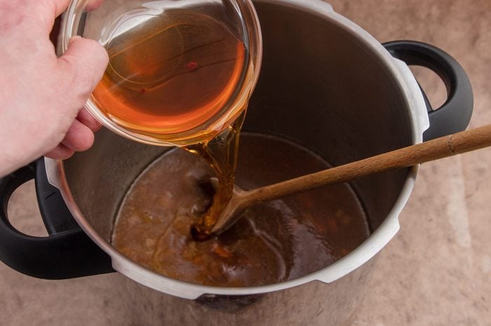 Pouring apple cider vinegar in pressure cooked beef gravy.