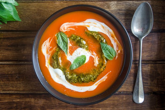 Tomato Soup With Pesto And Soured Cream In A Bowl And A Spoon On Wooden Background