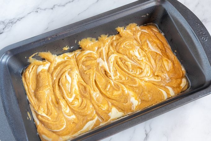 showing how to make pumpkin bread with cream cheese swirls in loaf pan