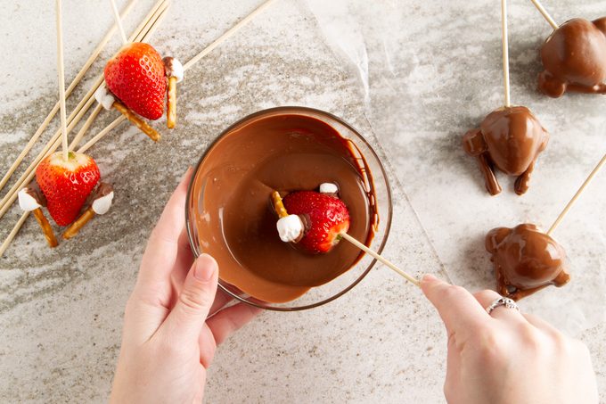 dipping turkey into chocolate for chocolate covered strawberry turkeys