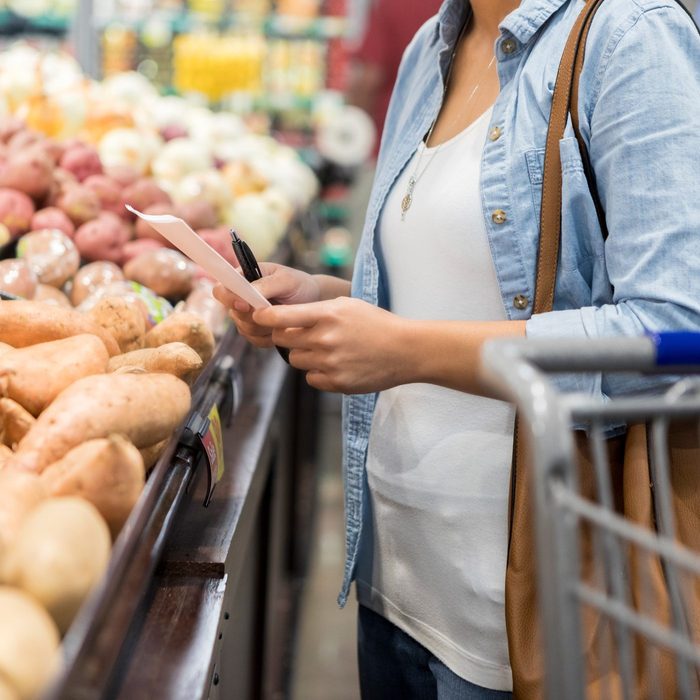 Woman looks at shopping list while in the grocery store