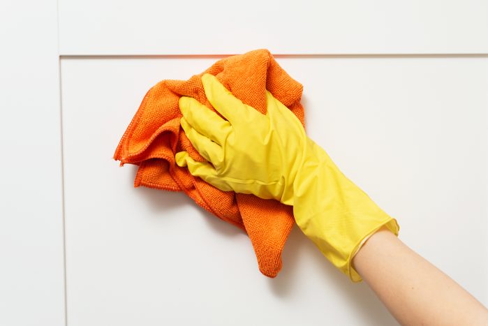cleaning white kitchen cabinets with an orange microfiber cloth