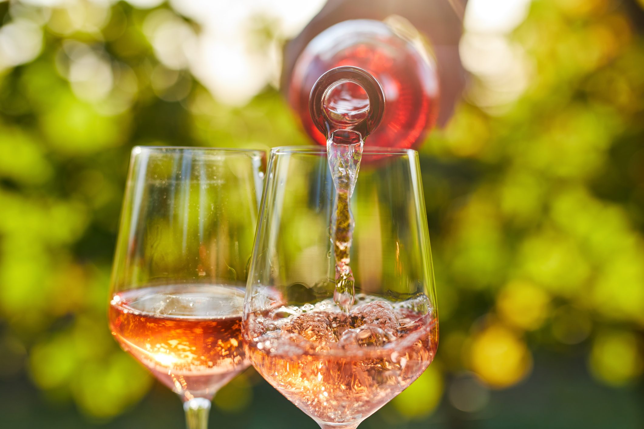 Pouring rose wine into a glass outside on a sunny day