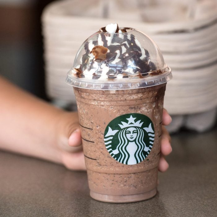 hand grabbing a starbucks frappuccino off the counter