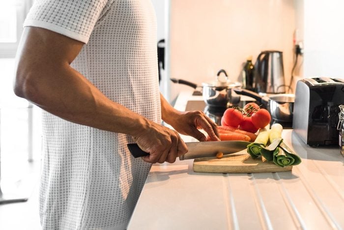 man cutting vegetables in kitchen