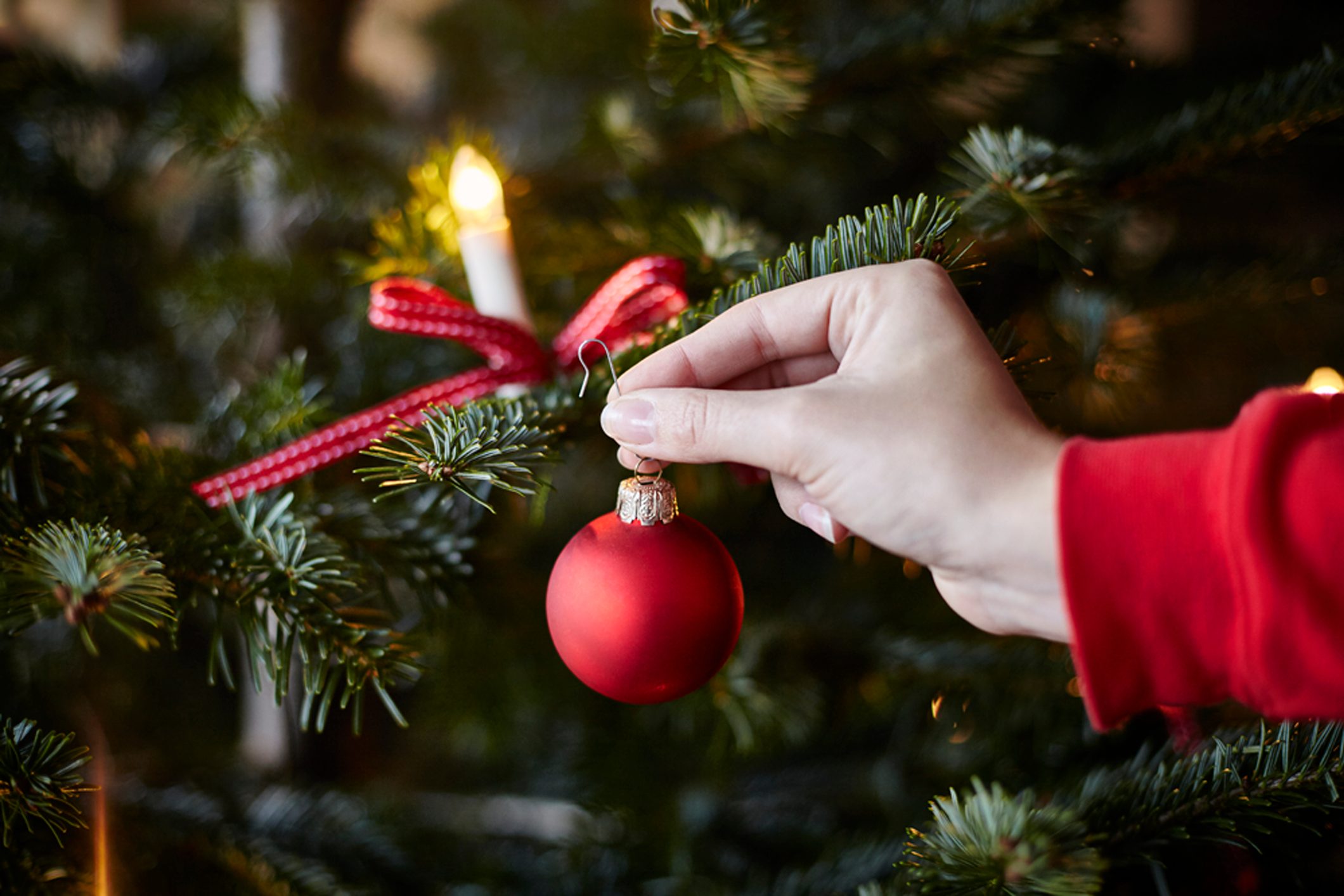 Young woman hanging ornament on Christmas tree