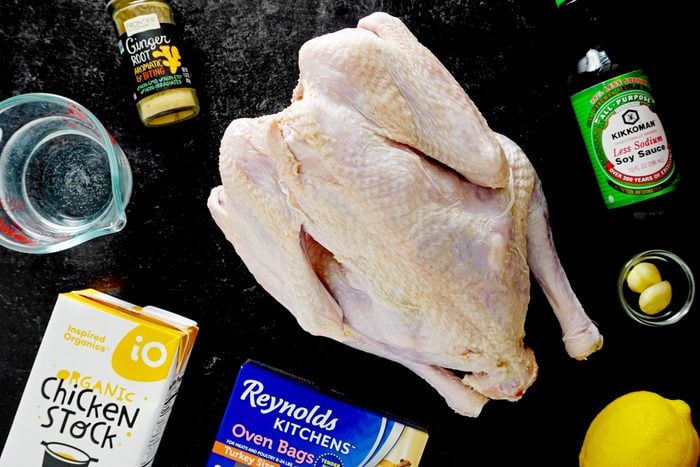 raw turkey and other ingredients for grilling turkey on a dark countertop
