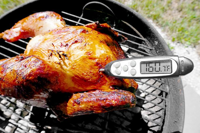 a digital meat thermometer in the grilled turkey showing 160 degrees