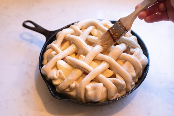 Brushing egg wash onto Apple Pie With Pretzel Crust