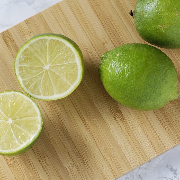whole and cut limes on cutting board