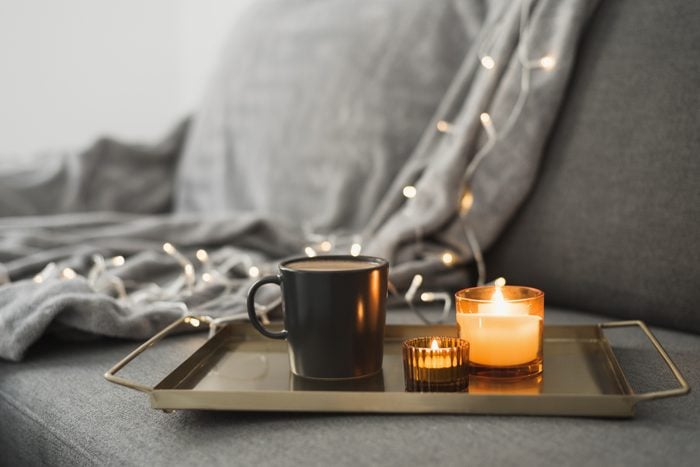 Hot coffee and two burning aroma candles on a metal tray