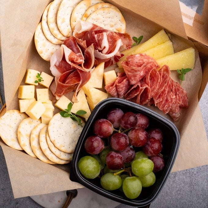 individual charcuterie box with cheese, meats, and grapes