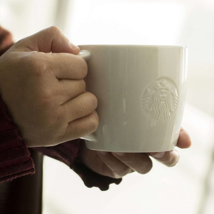A customer holding a Starbucks coffee cup. At the end of...