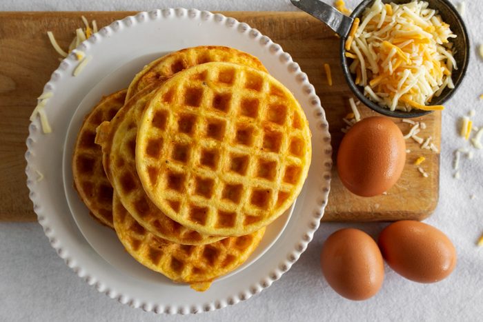 Cooked Chaffles on plate next to eggs and cheese on wood board