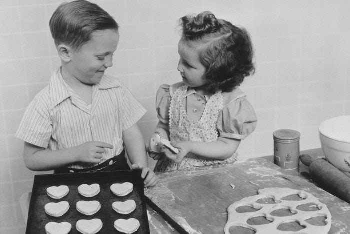 1940s YOUNG SMILING GIRL AND BOY BAKING HEART SHAPED VALENTINE COOKIES (Photo by H. Armstrong Roberts/ClassicStock/Getty Images)