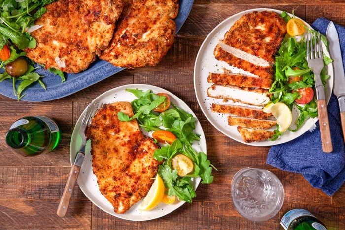 Air Fryer Chicken Cutlets Served in Plates with Leafy Greens on Wooden Surface