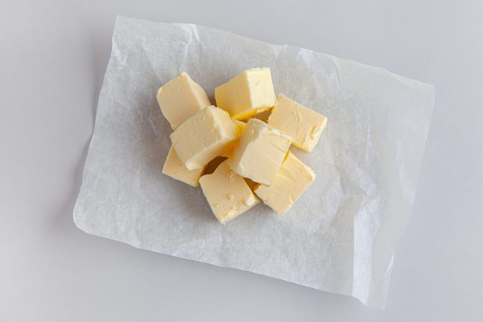 pieces of butter on wrapping paper on grey kitchen table background