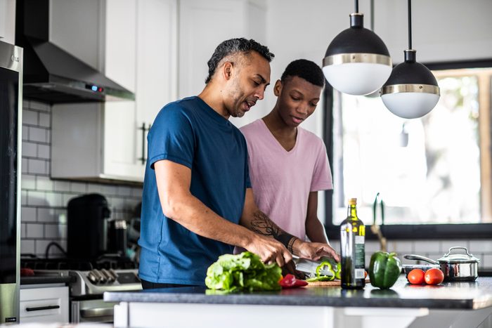 Father and teenage son cooking together in kitchen