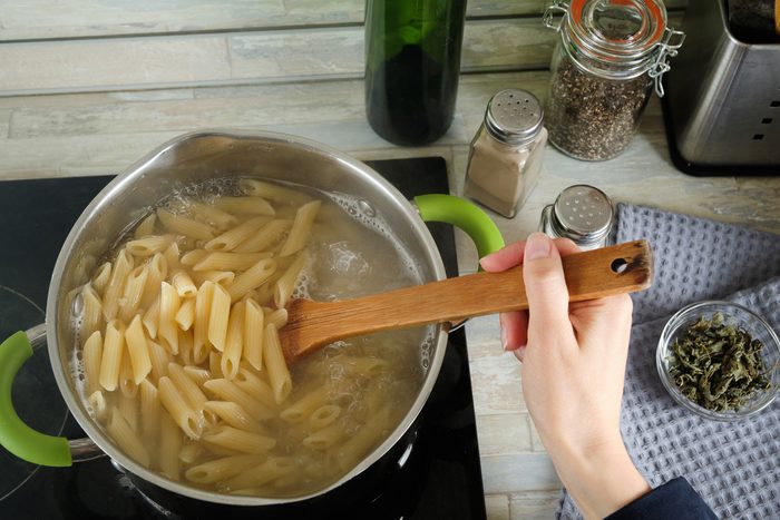 Cooking Italian pasta with cream sauce and Basil, at home. A girl or woman Cooks and Stirs Penne Pasta in a Pot. Vegetarian food. Step-by-step instructions, do it yourself. Step 4.