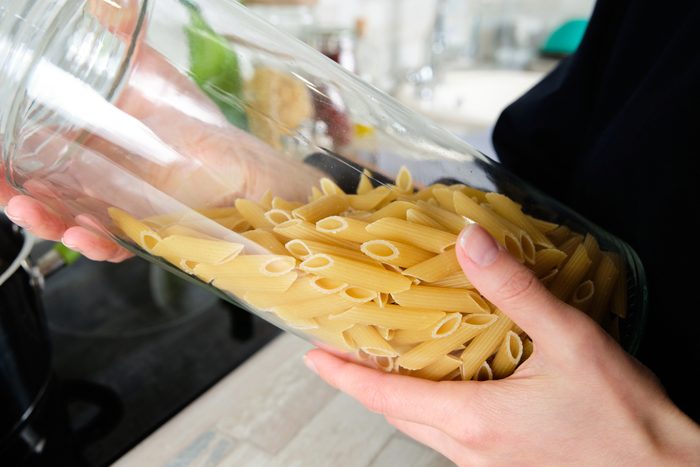 Cooking Italian Pasta With Cream Sauce and Basil, at Home. Choice Of Macaroni. A girl or Woman Holds Raw Penne Rigate Pasta in a glass storage jar. vegetarian food. Step-by-step instructions, do it yourself. Step 1.