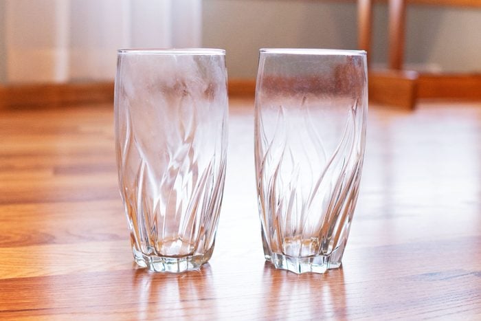 white film on glassware next to one clear glass on a wood surface