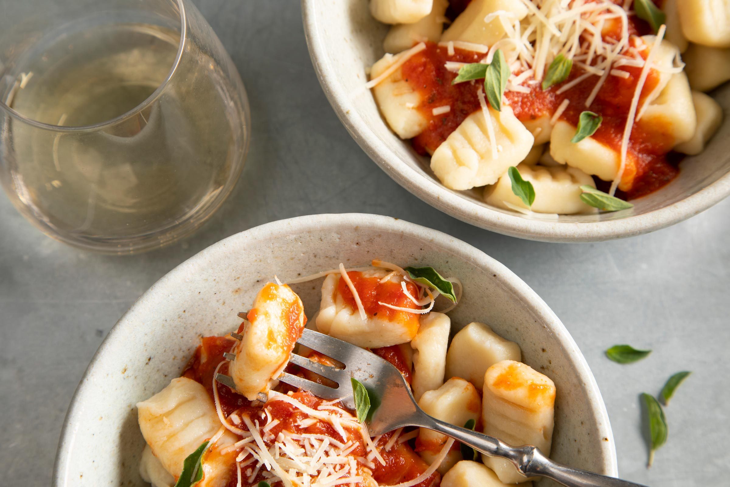 close up of Homemade Gnocchi served in two bowls with sauce and cheese