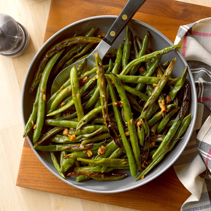 Sesame Soy String Beans on a gray plate on a cutting board on a light wood table