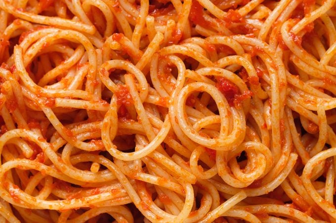 Spaghetti or pasta bolognese in tomato sauce on a ceramic plate, on a white background or table. The concept of Vegetarian and Vegan Food. Food background.