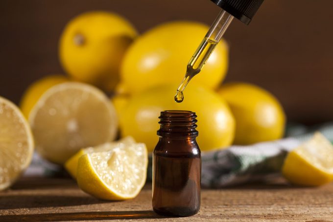 Lemon essential oil extract with lemons in the background