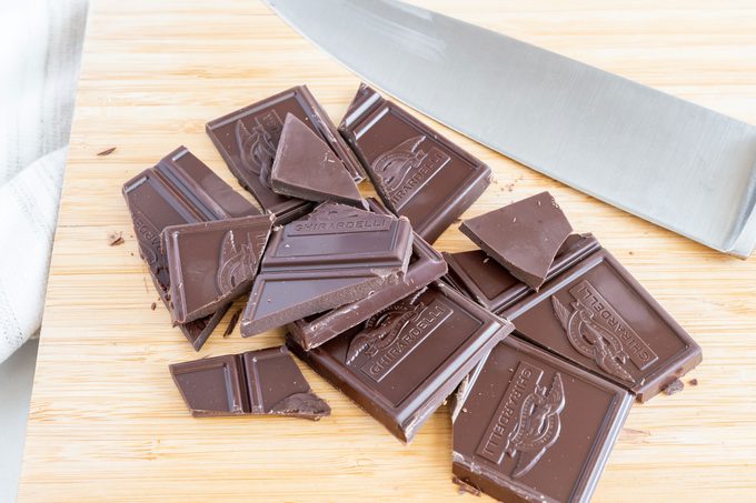 cut up chocolate pieces on a cutting board next to a knife