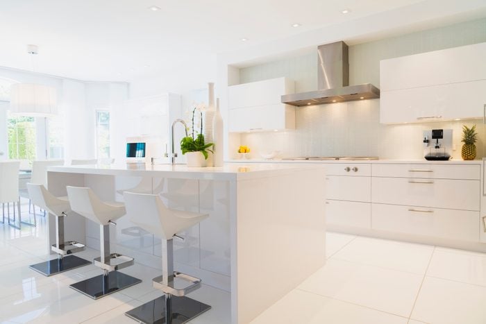 Modern kitchen with white Italian lacquered kitchen island and chrome barstools inside luxury residential home