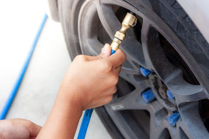 Cropped Hand Of Person Filling Air In Car Tire