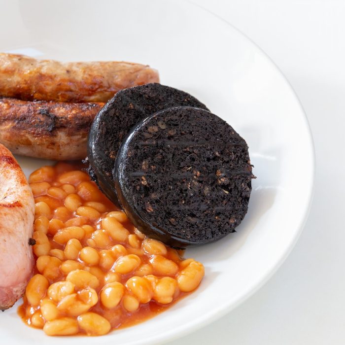 Cumberland sausages, bacon, baked beans and black pudding in a white bowl