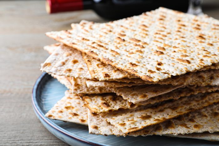 Stack of traditional matzos on wooden table, closeup
