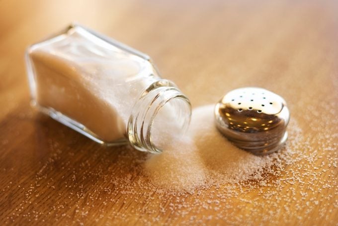 Spilled salt shaker on wood background