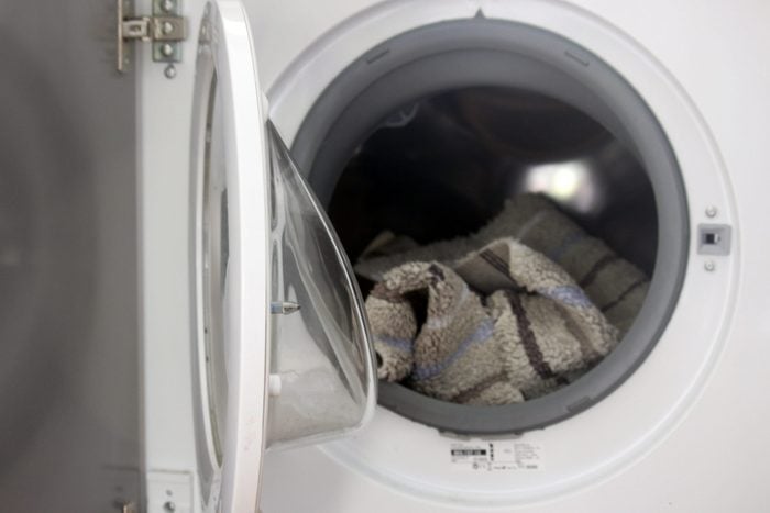 open washing machine revealing a bath mat inside the drum