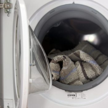 open washing machine revealing a bath mat inside the drum