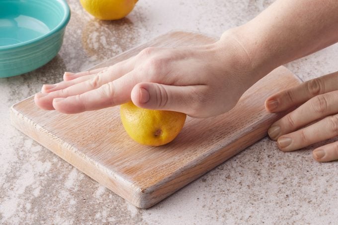 rolling a lemon on a cutting board