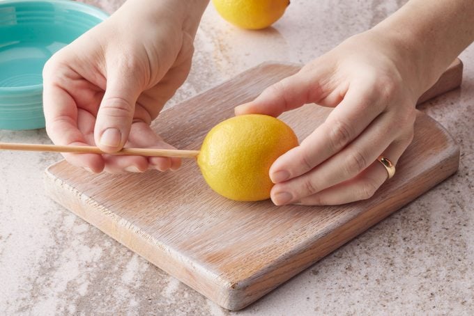 poking a hole In a lemon with a small wooden stick