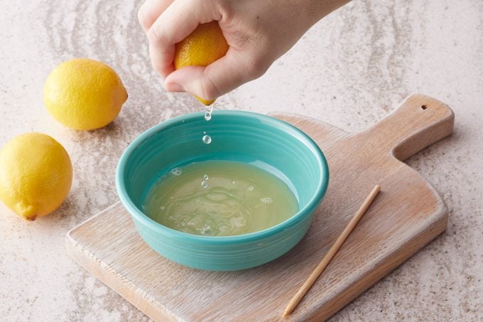 squeezing a lemon into a teal bowl