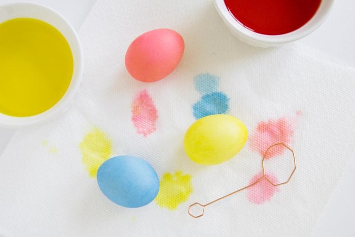 Dyed Easter Eggs on a paper towel near cups of dye