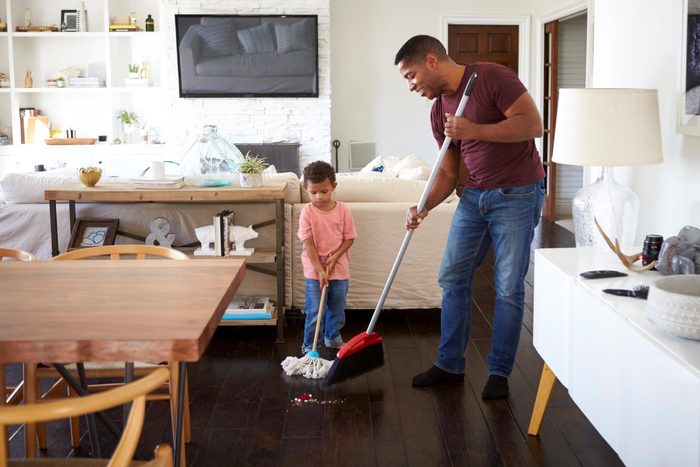 father and his young son mopping and sweeping the dining room floor