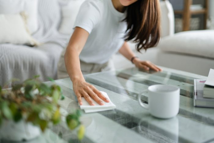 woman cleaning a coffee table in her living room