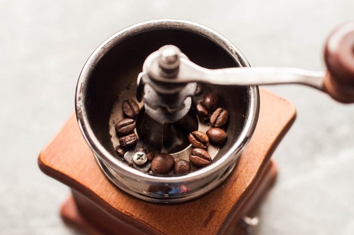 Hands are Grinding Coffee Beans On A Manual Coffee Grinder