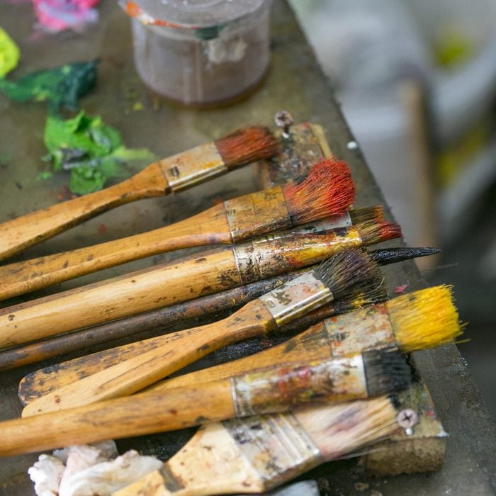 An artist's palette with open tubes of paint, brushes and a palette knife. Focus is on the brushes