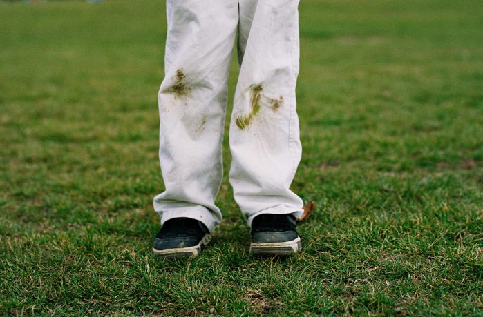 Boy holding soccer ball on field with grassy knees