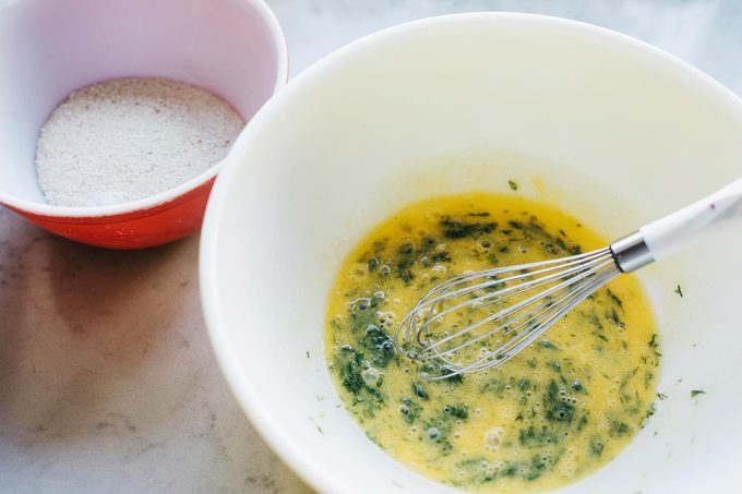 two mixing bowls, one with breadcrumbs and the other with eggs and a whisk